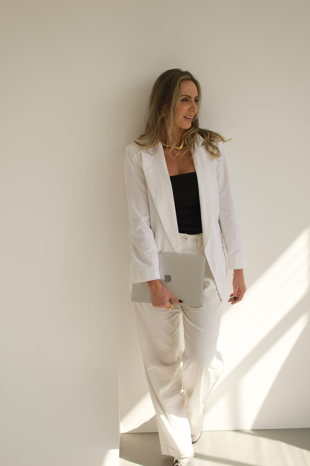 Keila Ventura de blazer branco segurando um notebook